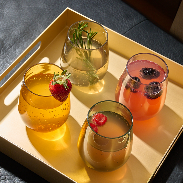 four tossware glasses filled with cocktails on a serving tray